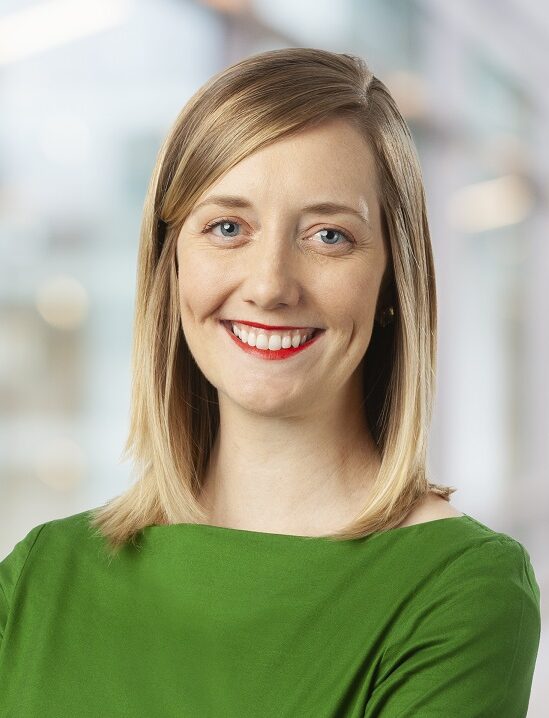 A white woman with blond hair wearing a green top