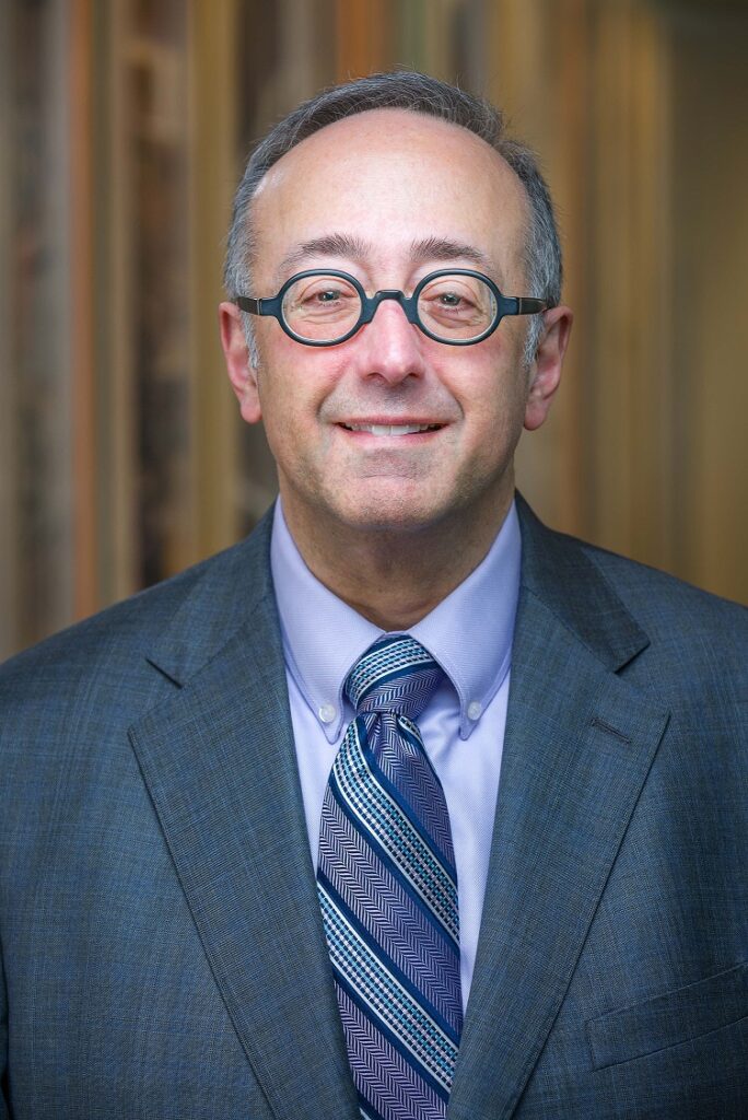 A white man in a suit wearing glasses