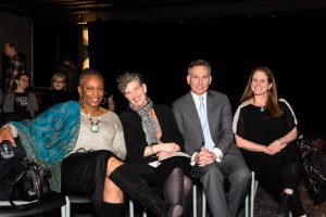 Four individuals sitting together at an event.