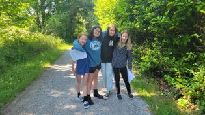 A group of children on a trail in the outdoors all smiling towards the camera.