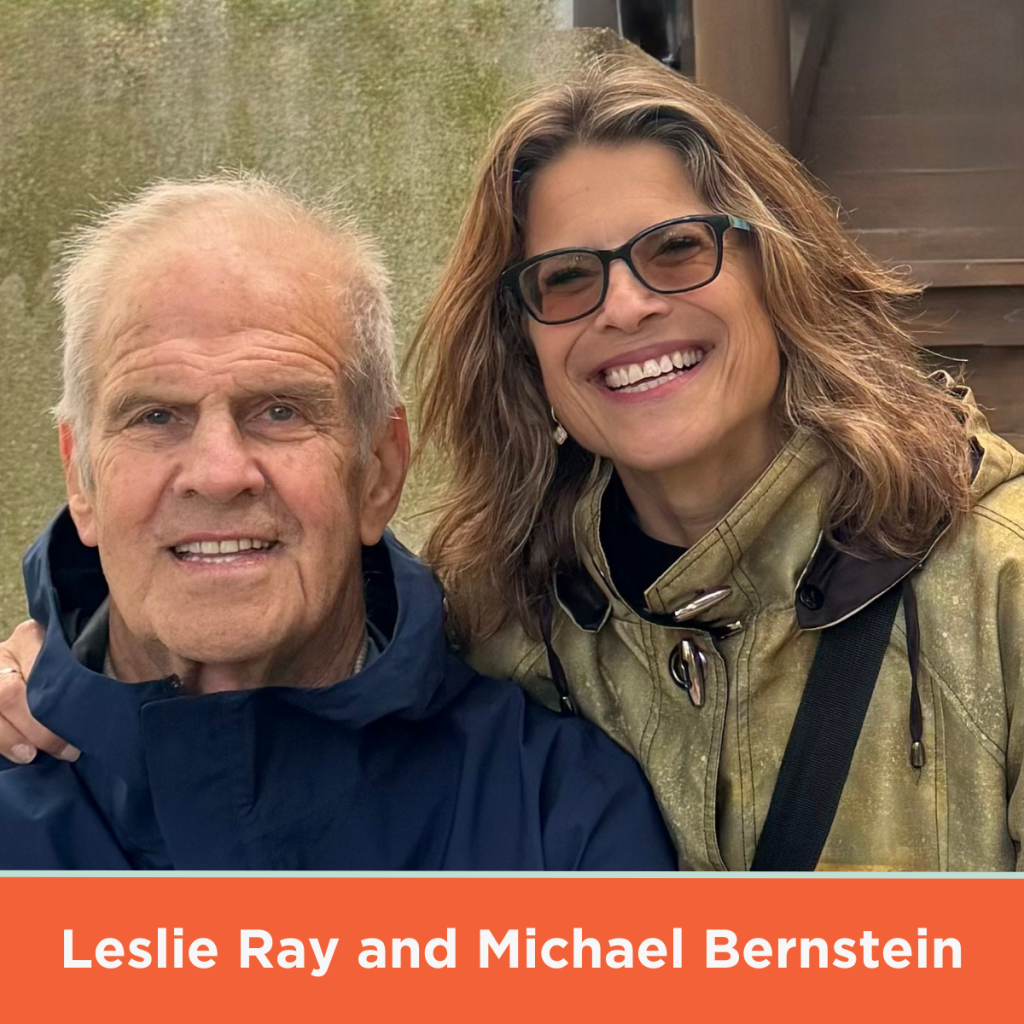 Donors Leslie Ray and Michael Bernstein smile wide. They are wearing blue and greenish-brown raincoats.