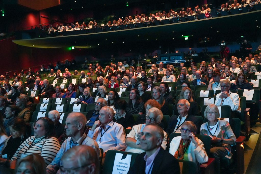 Donors sit in the auditorium seats of McCall Hall, listening and watching intently.