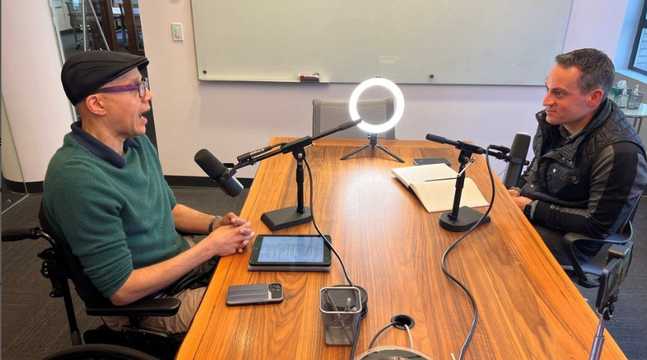 ArtsFund's CEO & President Michael Greer sits across an adult man in a recording studio. They're recording a podcast episode.