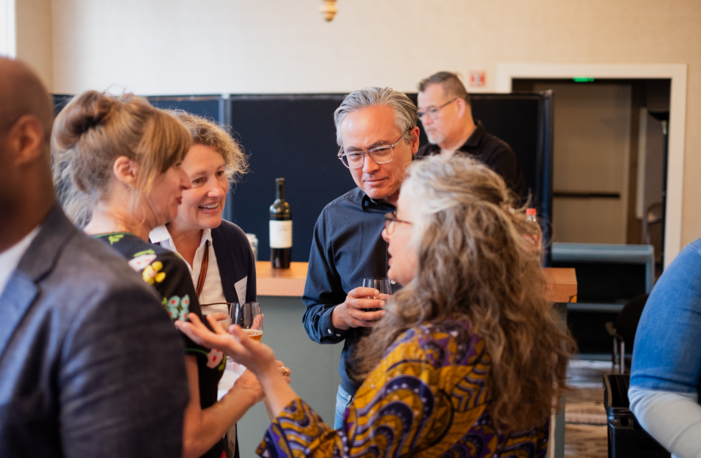 A group of professionals from arts nonprofits chat in a conference room.